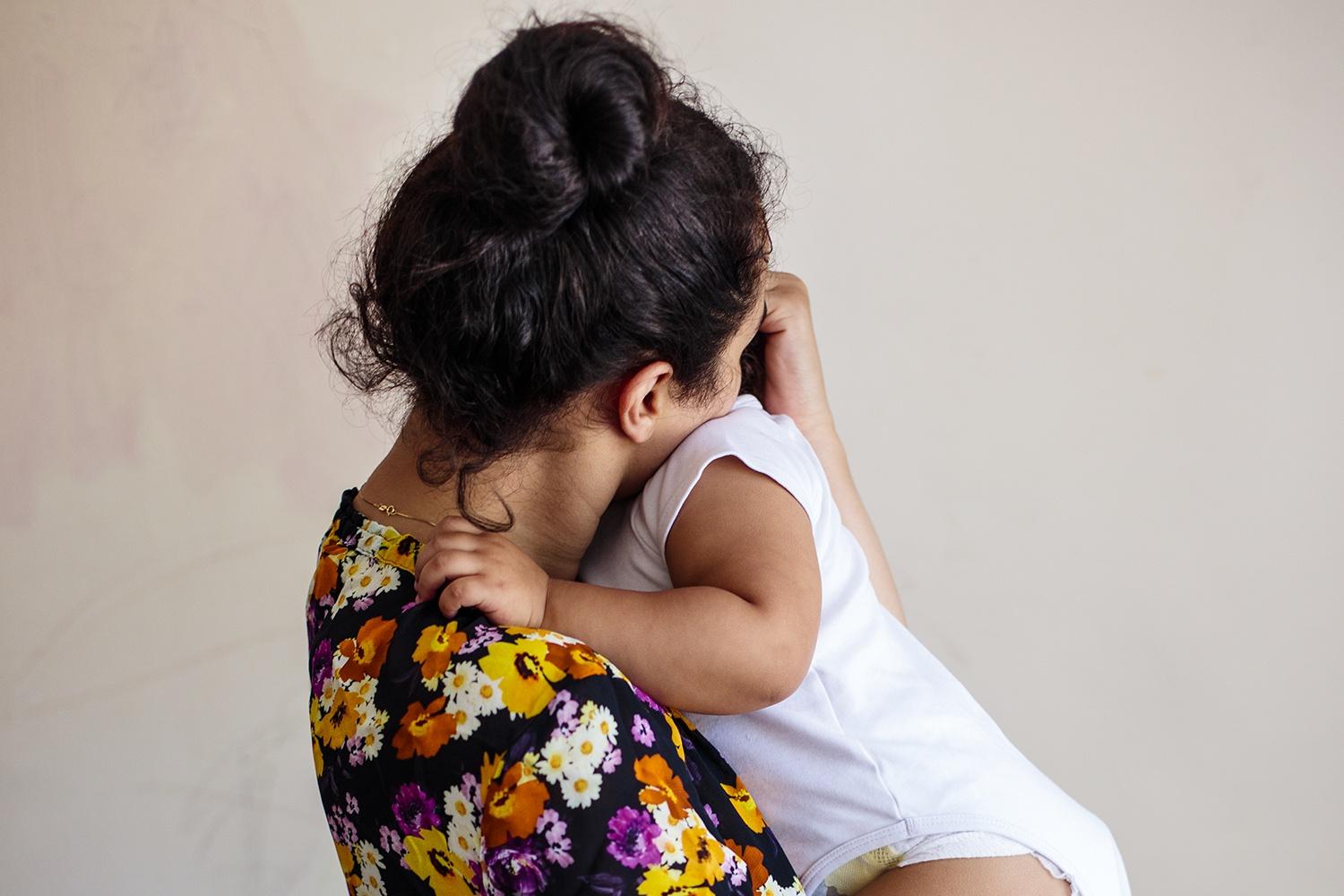 Young mum with face nestled into the baby she's holding